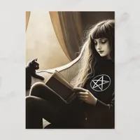 A witch reads with her black kitten postcard