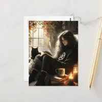 A witch reads with her black cat in a cozy chair postcard